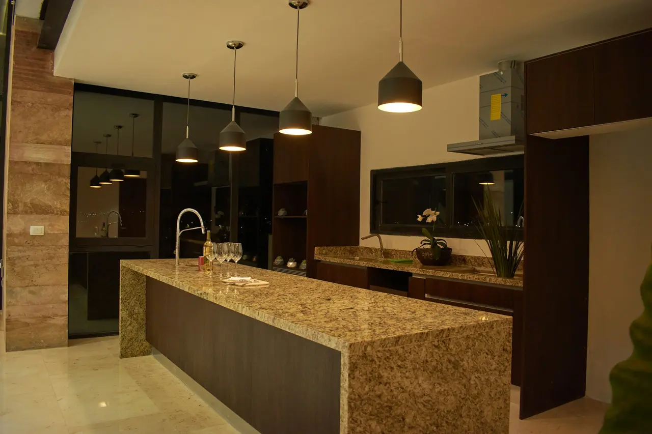 Cozinha ampla com ilha em granito dourado e armários escuros