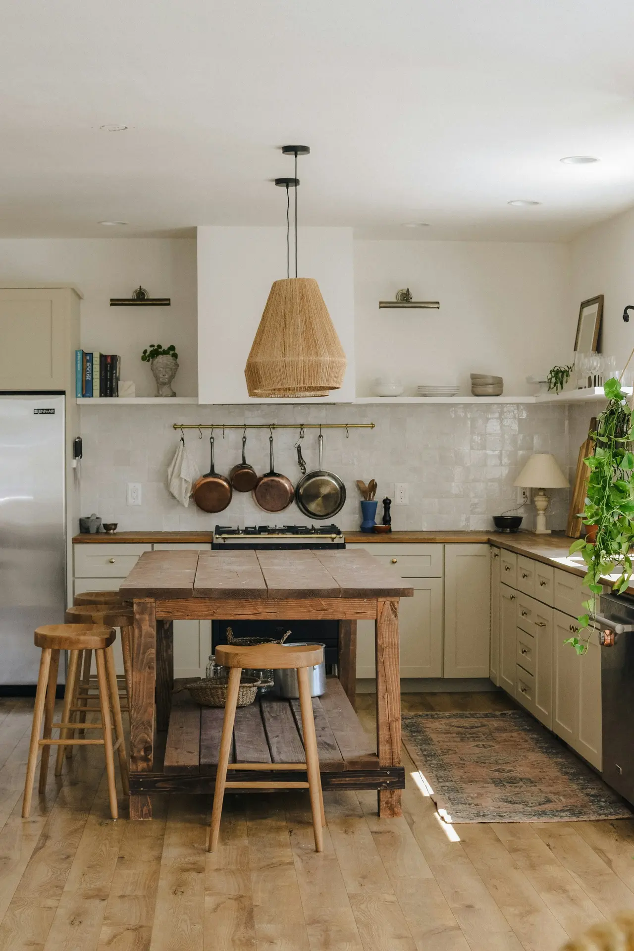 Cozinha rústica com ilha de madeira, banquetas e luminária de palha
